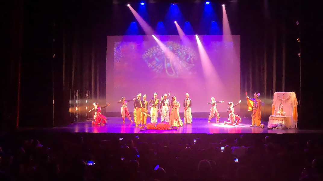 Ensemble in kleurrijke kostuums onder paars en blauw licht
