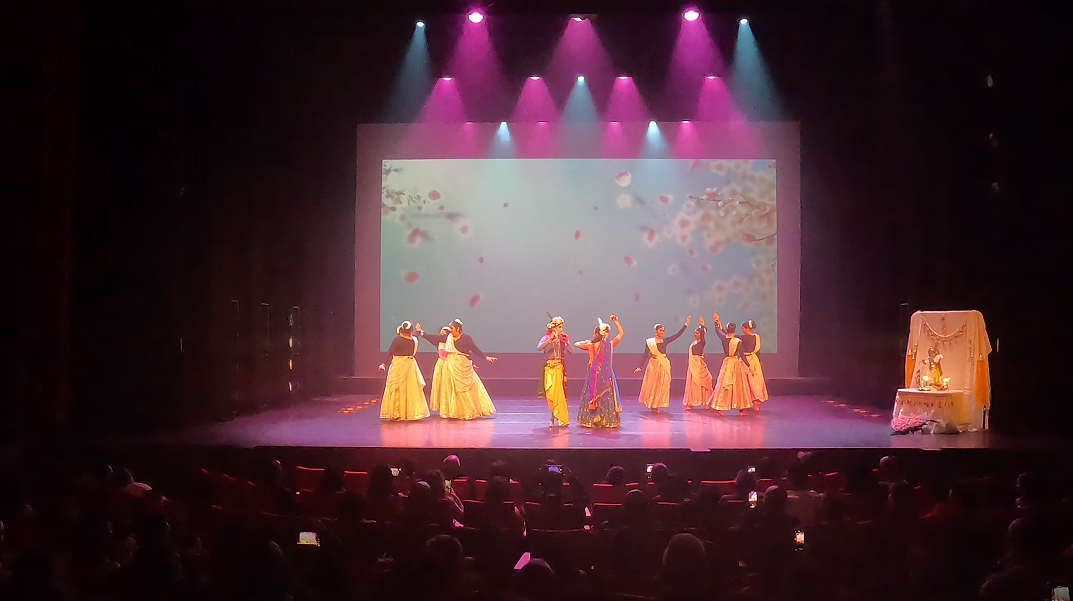 Dansers in gele kostuums onder roze belichting op het toneel